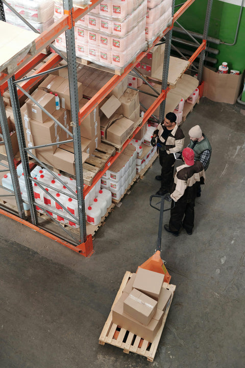 Trabajadores diligentes en un almacén espacioso de IBERAHOME.COM preparando cuidadosamente un pedido para envío.