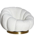 Sillón giratorio estilo art deco tapizado en bouclé blanco con base dorada.